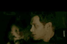 a close up of a man 's face in a dark room with a reflection of a woman