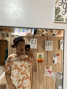 a man taking a picture of himself in front of a wall that says ' yi im '
