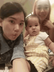 two women are posing for a picture with a baby girl .
