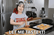 a woman wearing a shirt that says hunny let me taste it is cooking