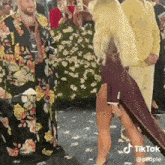 a woman in a high slit dress is walking down a runway at a wedding .