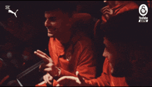 a man in a red shirt is looking at a cell phone with a youtube logo in the background