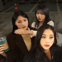 three girls are standing next to each other in a parking lot .