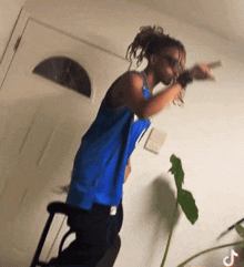 a man in a blue tank top is standing in front of a door holding a gun