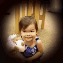 a little girl is holding a stuffed animal and smiling at the camera