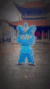 a person dressed in a blue lion costume is dancing in front of a building