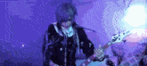a person with long hair is playing a bass guitar in a dark room .