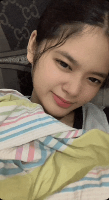 a girl laying on a bed with a striped blanket and a gucci blanket in the background