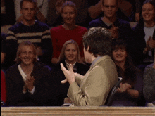 a man in a suit is clapping in front of a crowd