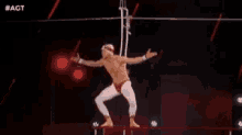 a man without a shirt is standing on a rope in a circus .