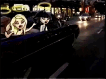 a couple of dolls are sitting in a car on a street at night