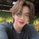 a young man wearing a blue shirt and red lipstick looks at the camera