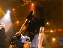 a man in a black shirt playing a guitar on stage