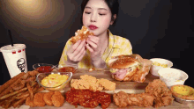 a woman is eating a chicken sandwich with a kfc drink