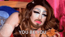 a drag queen with a beard is eating a pizza and says " you be you "
