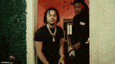 two men are standing in a doorway with one wearing a black shirt that says ' freedom ' on it