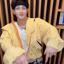 a young man wearing a yellow jacket and a headband is pointing at the camera .
