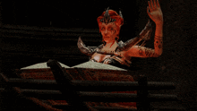 a woman with horns and a tattoo on her arm is sitting in a box