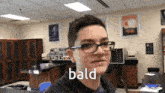 a young man wearing glasses and a black jacket says bald