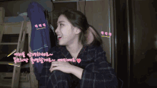 a woman in a plaid shirt is smiling in a room with korean writing around her