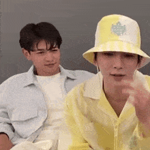 a couple of men are sitting next to each other wearing hats and shirts .