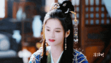 a woman wearing a blue and gold costume with chinese writing on the bottom
