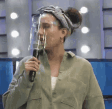 a woman wearing a face shield and holding a microphone .