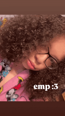 a girl with curly hair wearing glasses and a pink mickey mouse pajamas