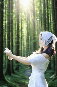 a woman in a white dress is standing in a forest holding a bottle