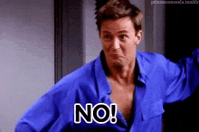 a man in a blue shirt is holding his shirt up and saying no .