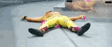 a wrestler is laying on the floor with his legs crossed .