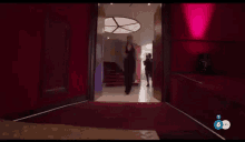 a woman in a black dress is walking down a red carpeted hallway