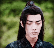 a man with long hair is wearing a ponytail and a ring on his head