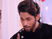 a man with a beard and earrings is making a funny face while wearing a black jacket .