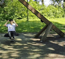 a man is sitting on a wooden swing in the park