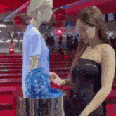two women are standing next to each other on a red carpet looking at a blue purse .
