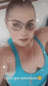 a woman wearing sunglasses and a blue tank top says claro que yeessss