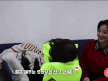 two women are sitting on a couch and one of them is wearing a neon green hoodie that says louis vuitton
