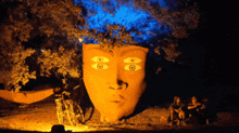 a statue of a woman 's face with three eyes and a tree in the background
