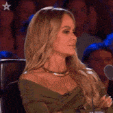 a woman in a green off the shoulder top is sitting in front of a microphone .