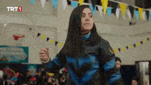 a girl in a blue and black jacket is standing in front of a sign that says trt1