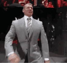 a man in a suit and tie is standing on a stage in a dark room .
