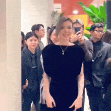 a woman in a black dress stands in front of a crowd of people