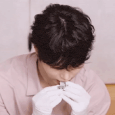 a man wearing white gloves is holding a piece of paper in his mouth