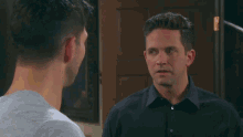 a man in a black shirt stands next to another man in a grey shirt