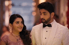 a man in a tuxedo and a woman in a pink dress are looking at each other .