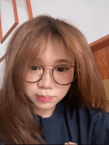 a young woman wearing glasses and a blue shirt looks at the camera