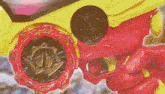 a person is holding a red and yellow toy gun with a gold coin on it .