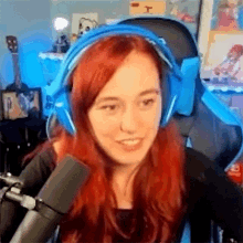 a woman with red hair is wearing a pair of blue headphones and a microphone .