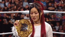 a woman in a white dress holds a gold wrestling championship belt
